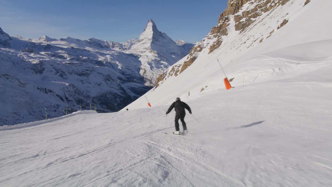 Skiing in Zermatt under the Matterhorn during a blue bird day and perfect slopes. High performance carving on skis.