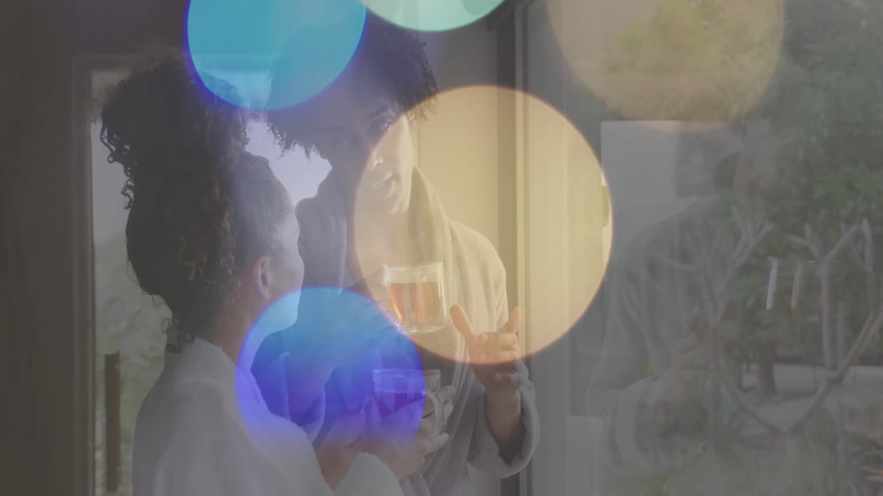 bebiendo té y hablando, pareja en túnicas de baño con animación de luces bokeh