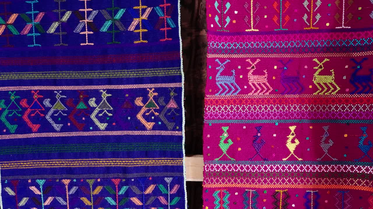 Handwoven Guatemalan textiles displaying colorful geometric and animal motifs