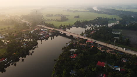 road bridge spanning across backwaters on a foggy sunrise in kerala, india