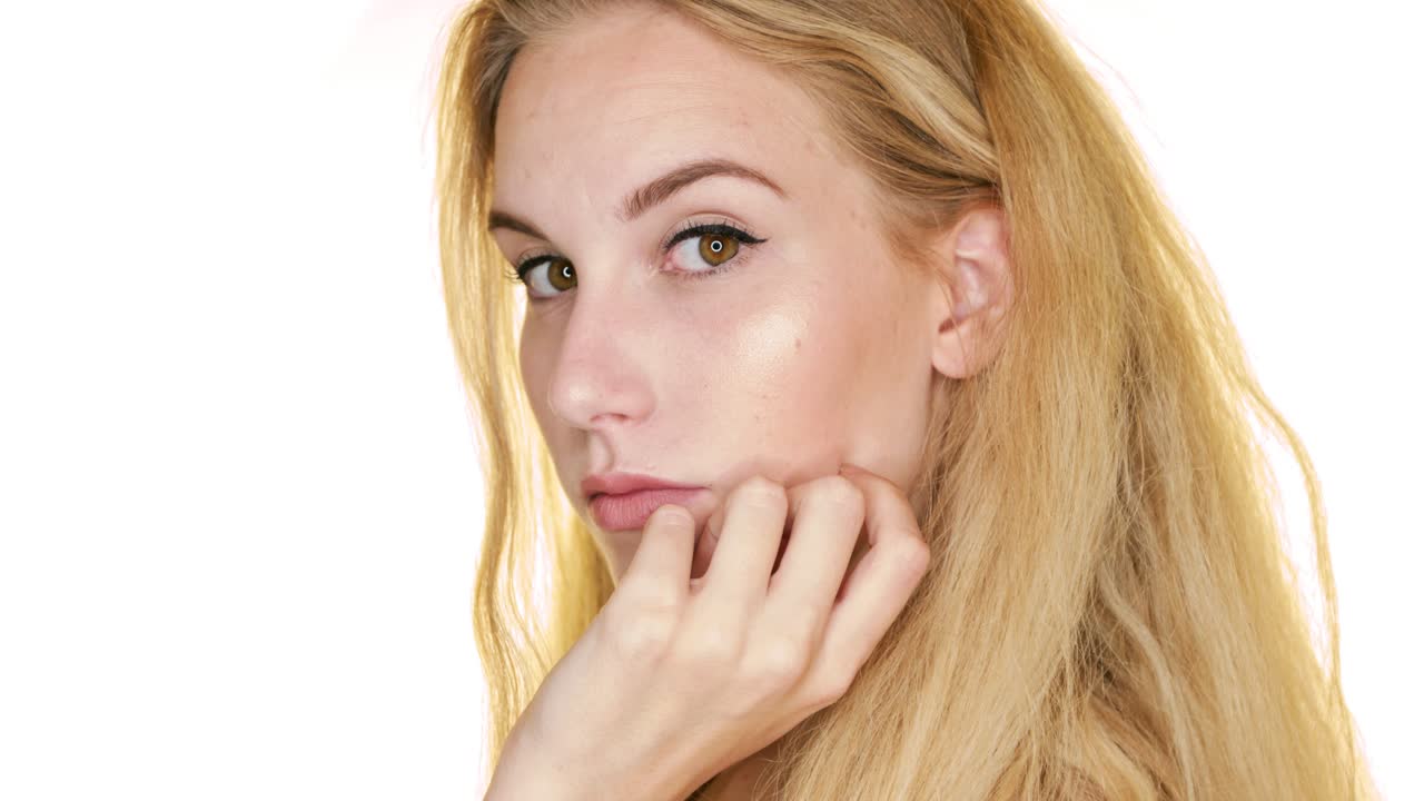 en cámara lenta, contra un fondo blanco, una mujer rubia posa con confianza