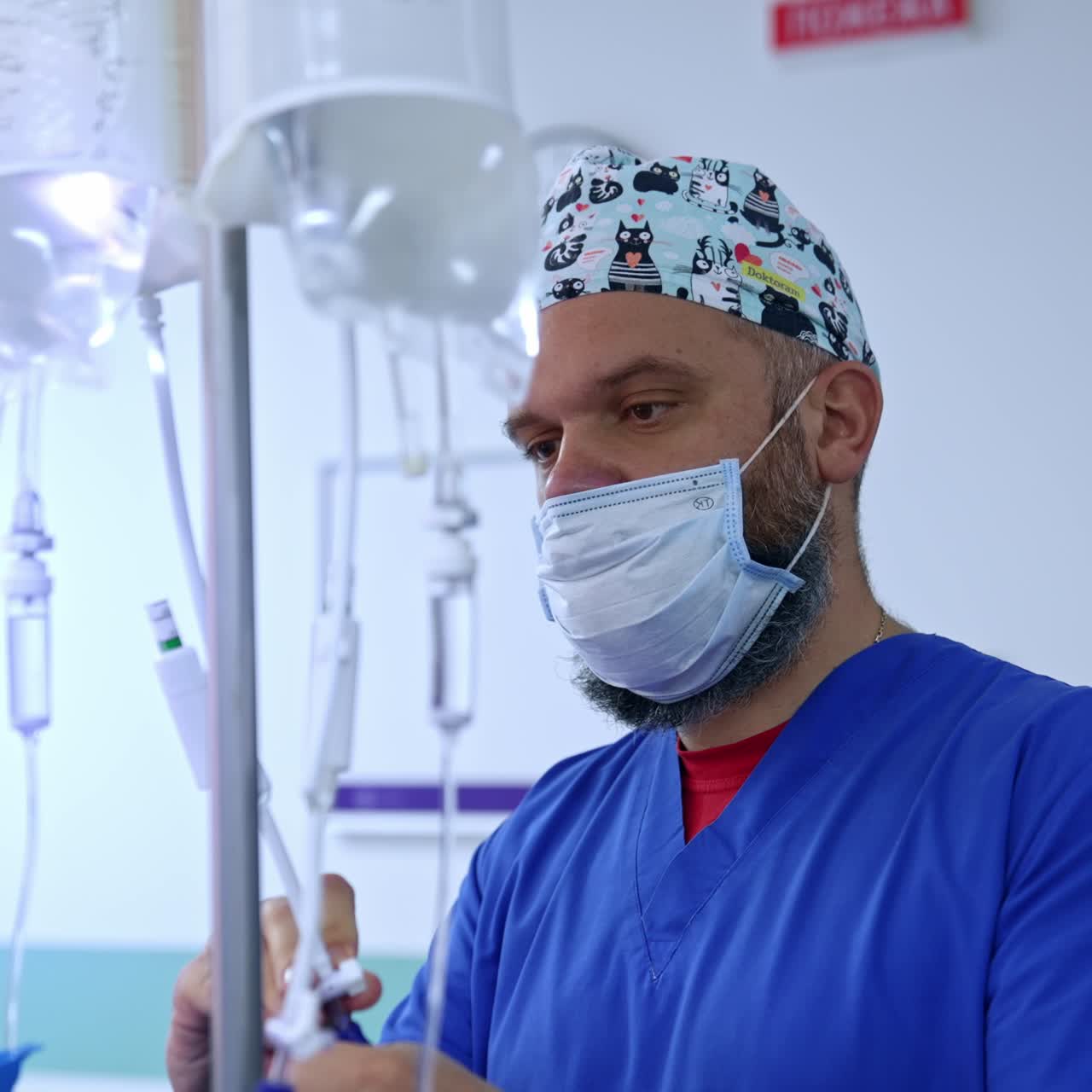Mid-aged bearded man in mask is preparing the drop counters before the surgery. Male anesthesiologist in modern surgical room