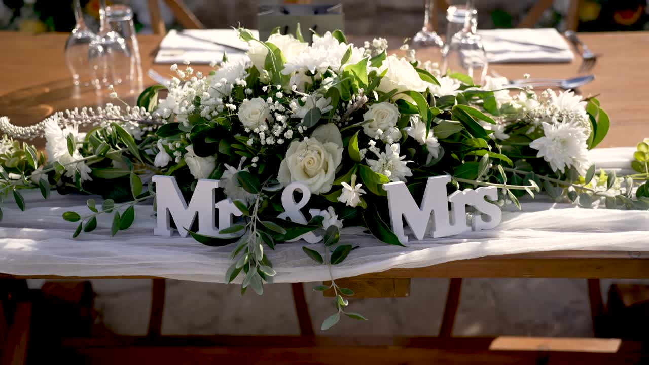 Fresh flowers and elegant decor create a stunning wedding display. The Mr. and Mrs. sign adds a personal touch to the charming outdoor setting for a perfect celebration