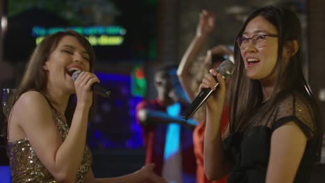 joyful women singing in karaoke bar