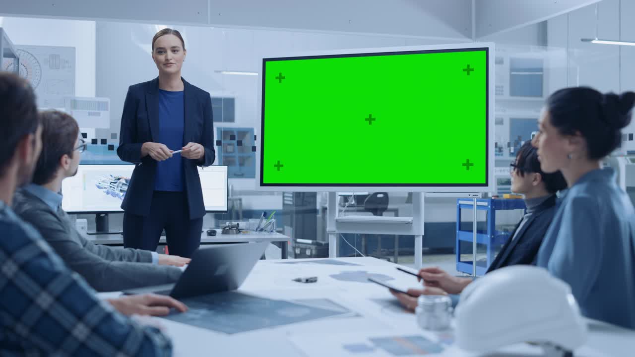 현대 산업 공장 회의: 자신감있는 여성 엔지니어가 인터랙티브 녹색 모형 화면 화이트 보드를 사용하여 엔지니어, 관리자 그룹에 보고합니다.