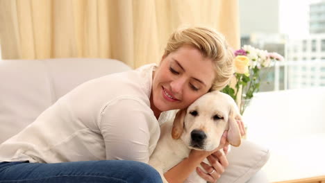 rubia feliz jugando con el cachorro en el sofá