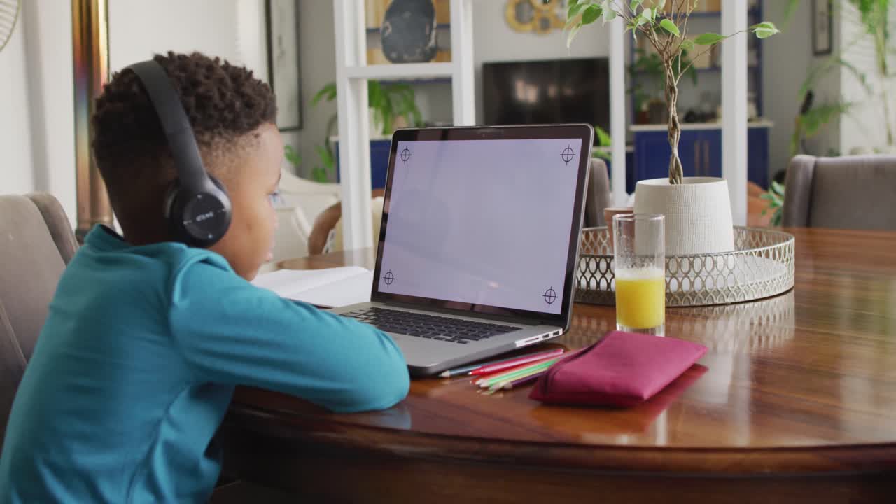 video de un niño afroamericano con auriculares aprendiendo con una computadora portátil con espacio para copiar