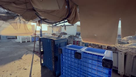 Fishing-warehouse-outdoor-environment,-moving-through-covered-stock-plastic-boxes-aimed-for-keeping-the-fish-cached
