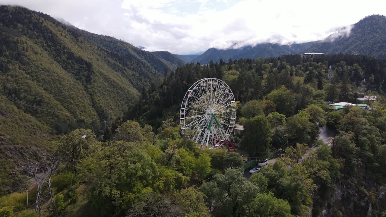 vista aérea de la rueda gigante en la cima de las montañas rodeada de bosque nube niebla valle ciudad