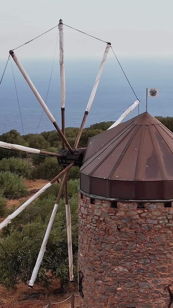 Mulino a vento tradizionale in pietra su una collina che si affaccia sul Mar Mediterraneo