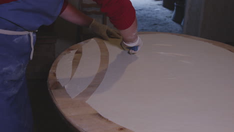 cook cutting raw dough with a knife - preparation of meat khinkali dumplings in georgia - close up