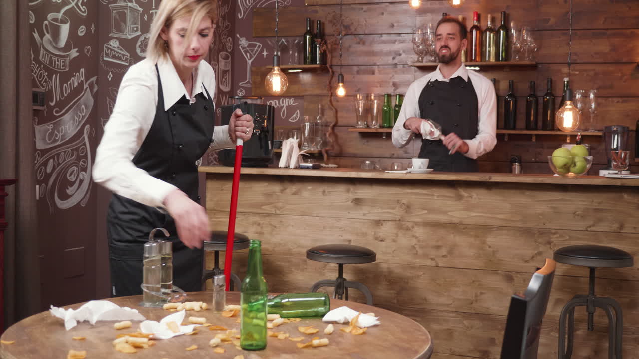 Waitress and Waiter Cleaning Messy Bar After Hours