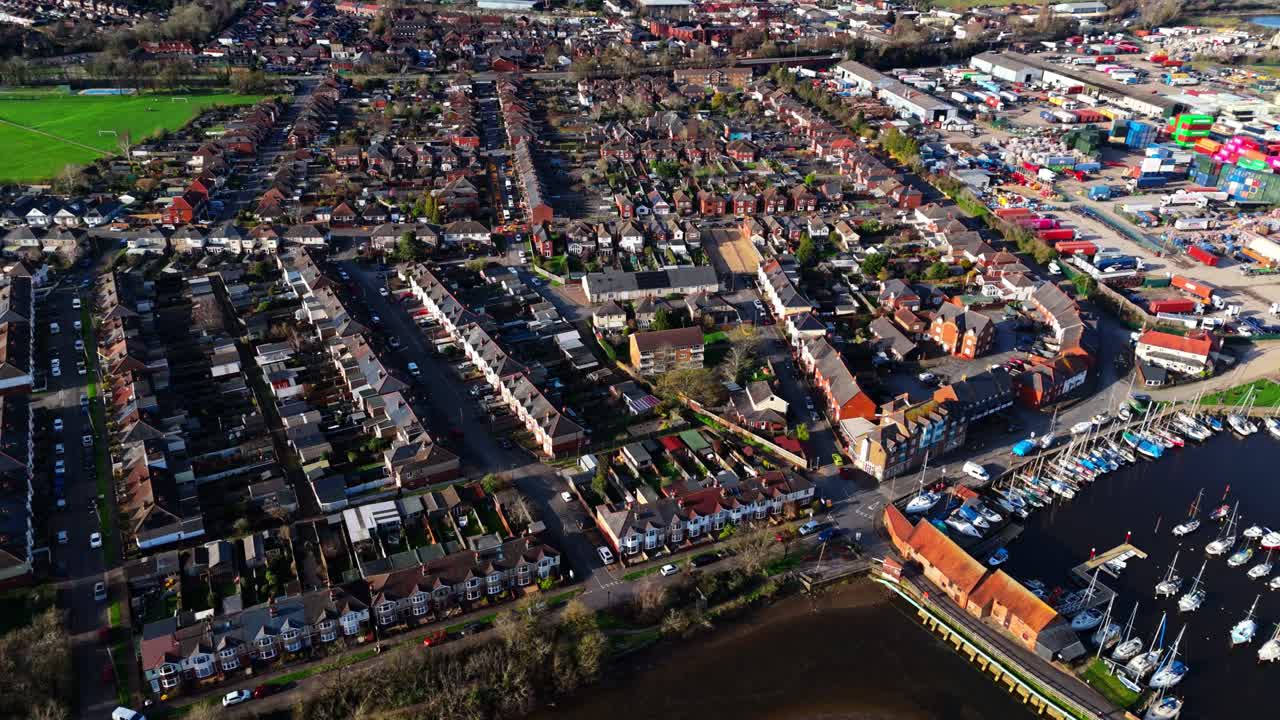Flugschwenk über den Vorort Totton westlich des Flusses in Southampton, England, mit Autos auf den belebten Straßen und Sonnenlicht, das sich im Winter auf dem blauen Flusswasser mit Booten darauf spiegelt