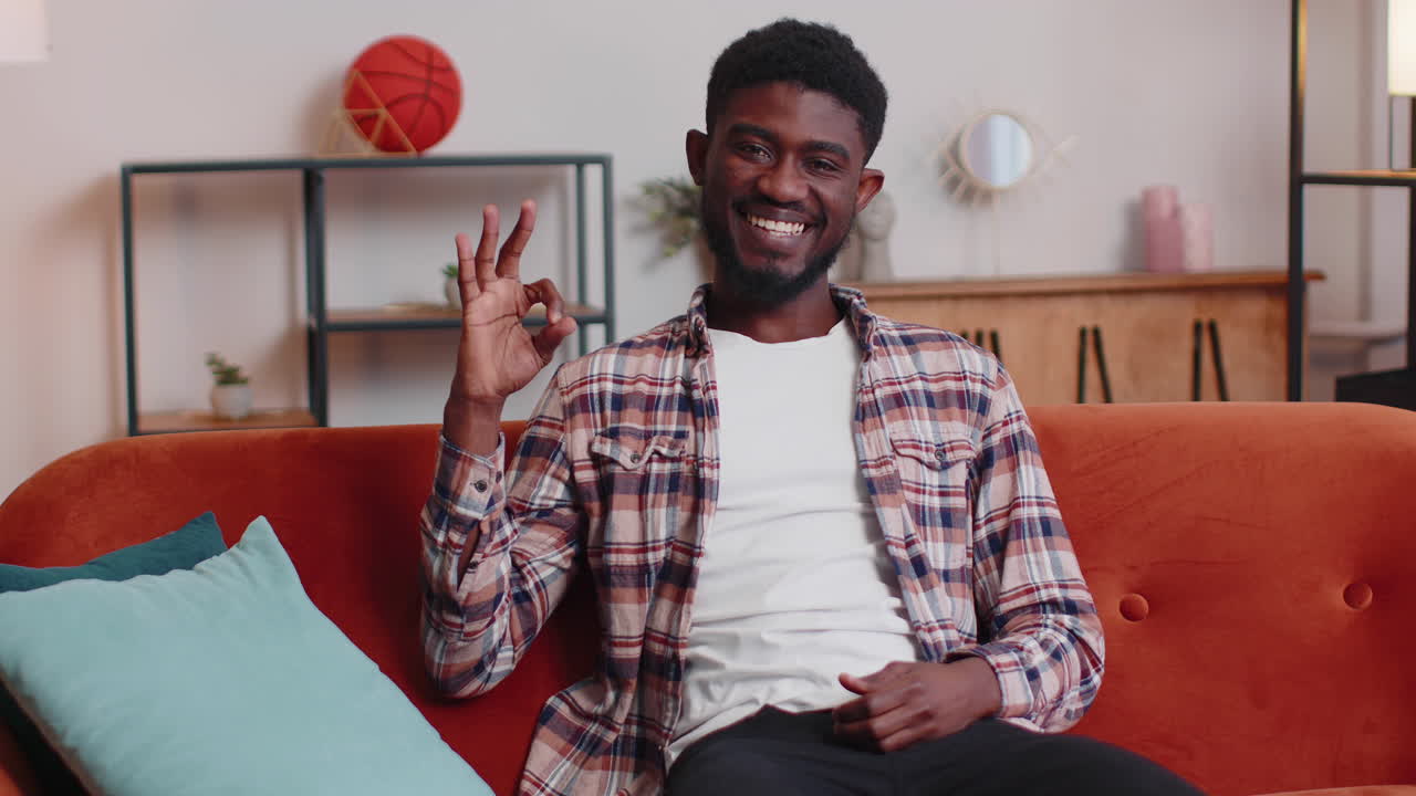 Uomo afroamericano che mostra il gesto dell'ok, come segno di qualcosa di positivo, dando una risposta affermativa a casa.
