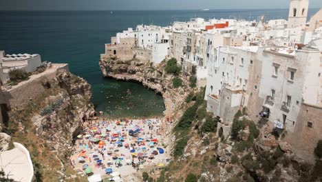 Drone-shot-overlooking-the-beach-in-Polignano-Mare,-Puglia