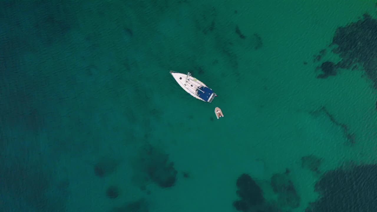 vista aérea que se eleva sobre un velero en el mar turquesa, mediterráneo, en la costa de mykonos, día oscuro y nublado, en grecia - destornillador, disparo de drones