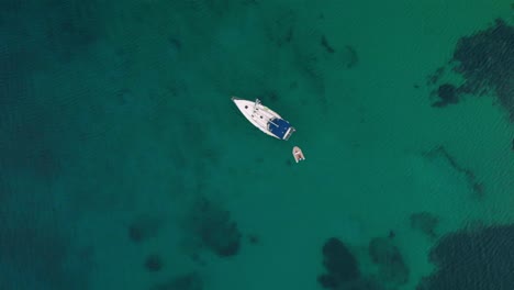 vista aérea que se eleva sobre un velero en el mar turquesa, mediterráneo, en la costa de mykonos, día oscuro y nublado, en grecia - destornillador, disparo de drones