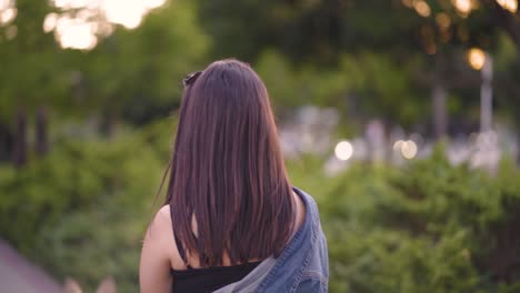 girl walking a dog in the park from the back