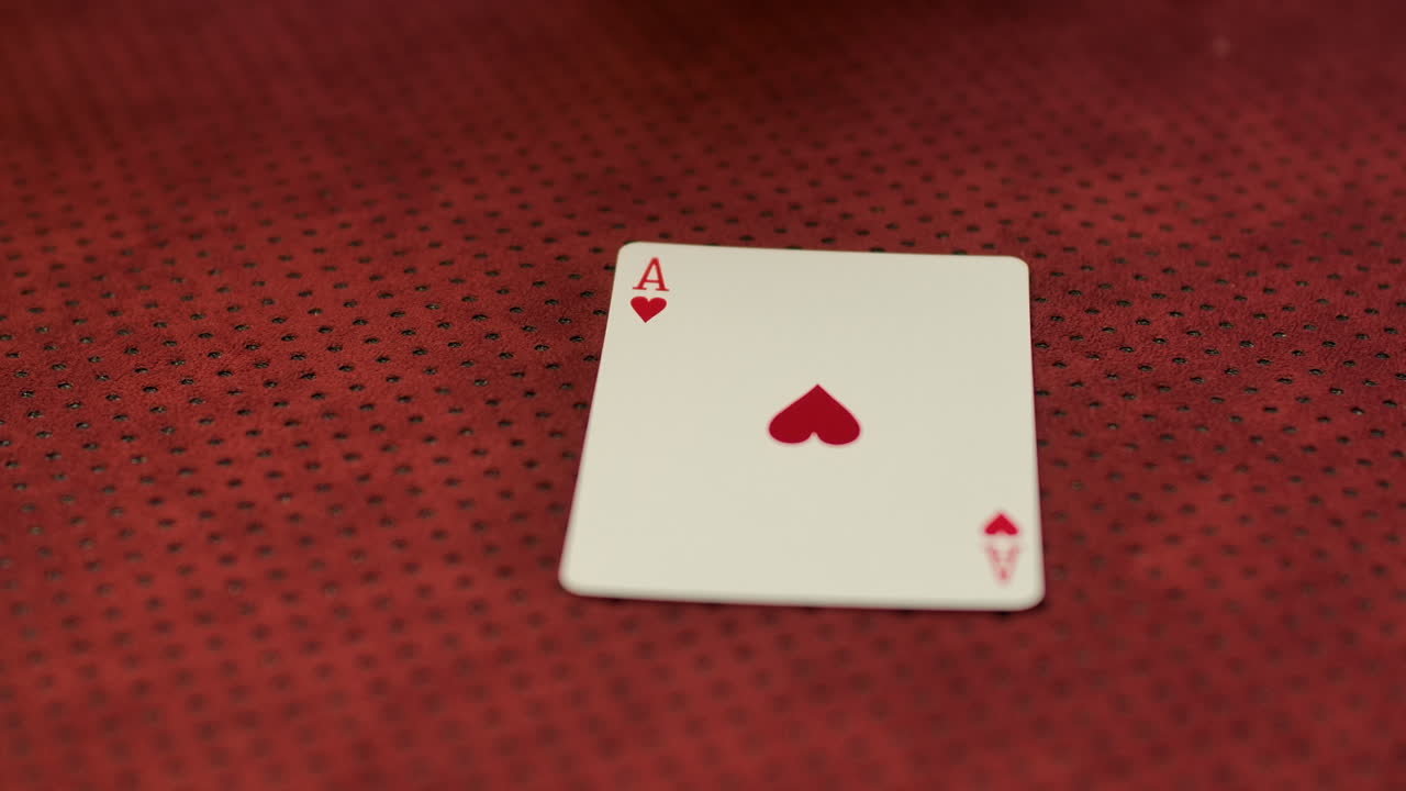 Slow motion closeup of a card dealer revealing an Ace of hearts on the game table
