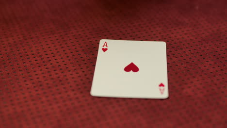 slow motion closeup of a card dealer revealing an ace of hearts on the game table