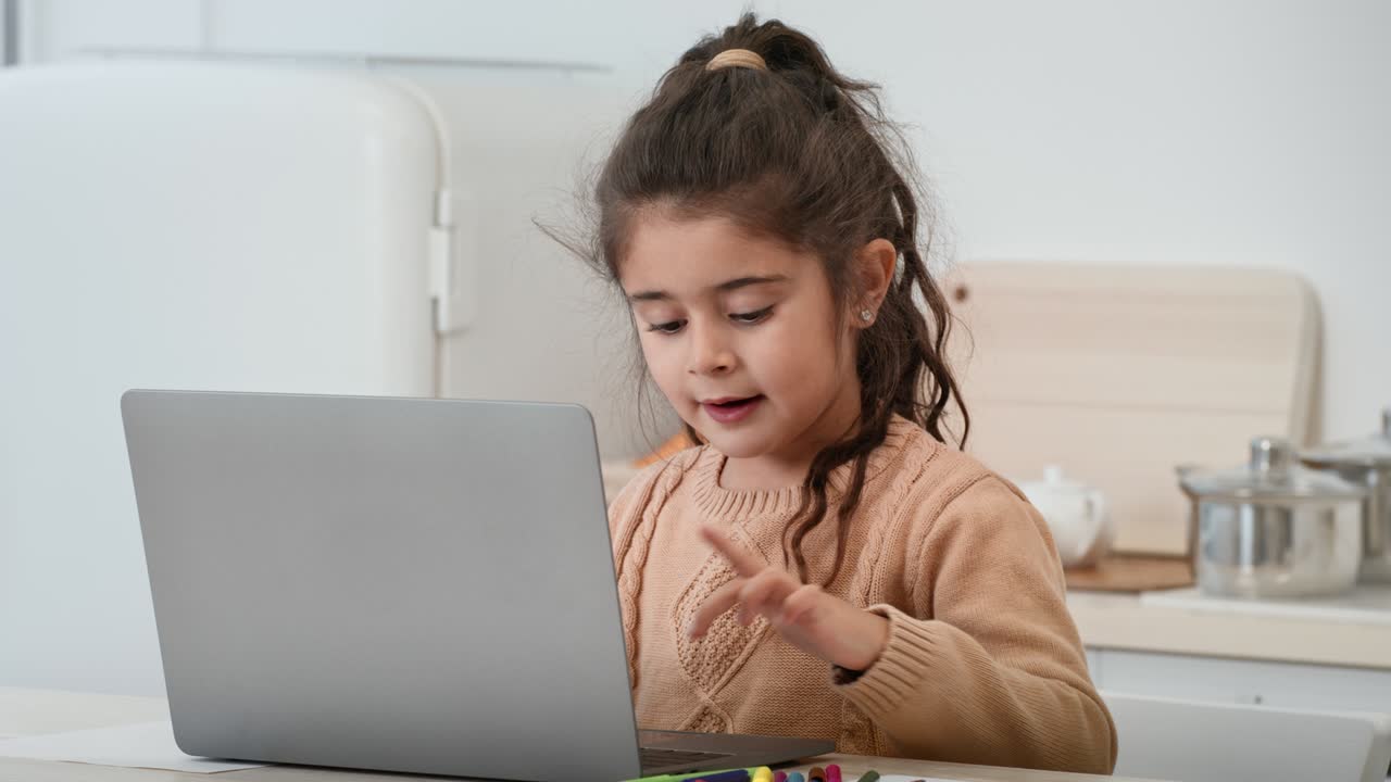 una niña árabe usando una computadora portátil escribiendo navegando por internet en la cocina