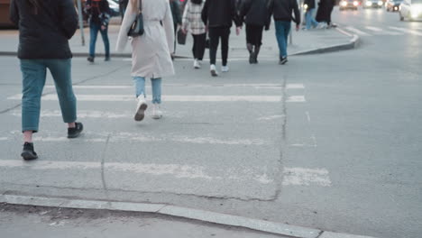 a city view featuring pedestrians walking across the street, and wearing different footwear and movement on the pavement