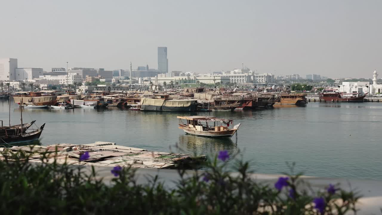 Marina with boats in Doha city with traffic and plants
