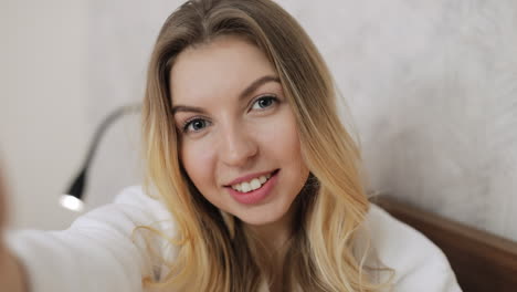 young woman taking a selfie in bed