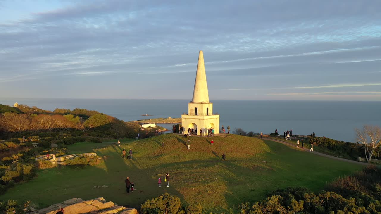Killiney Hill, Dublin, Ireland, Sunset, January 2020, Drone orbits Obelisk revealing views of Dun Laoghaire Harbour, Howth and Dublin Bay in the distance.