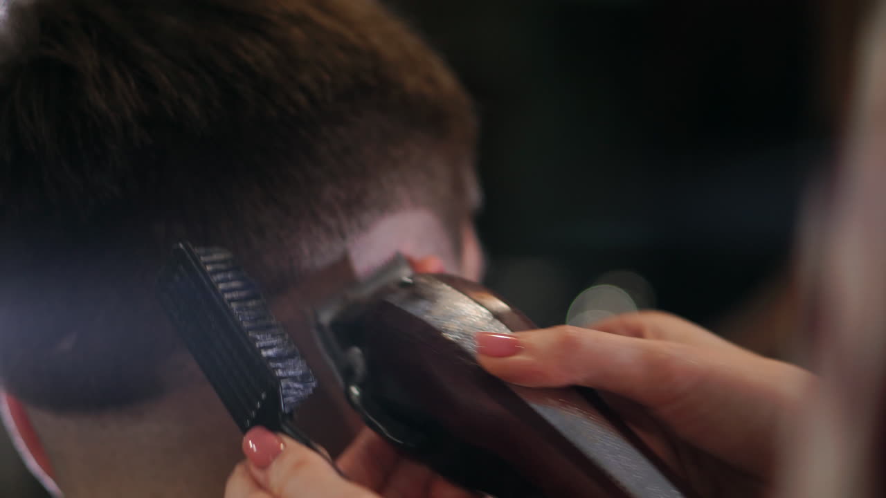 Close-up view on male's hairstyling in a barber shop with professional trimmer. Man's haircutting at hair salon with electric clipper. Grooming the hair.