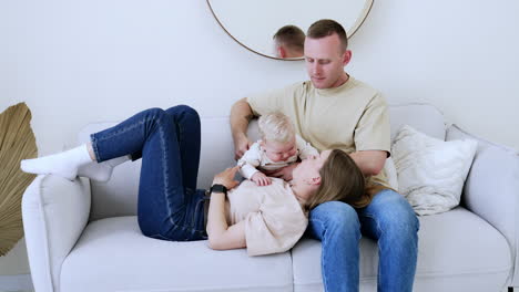 caucasian parents with their lovely baby boy on the sofa. happy family spending time at home together.