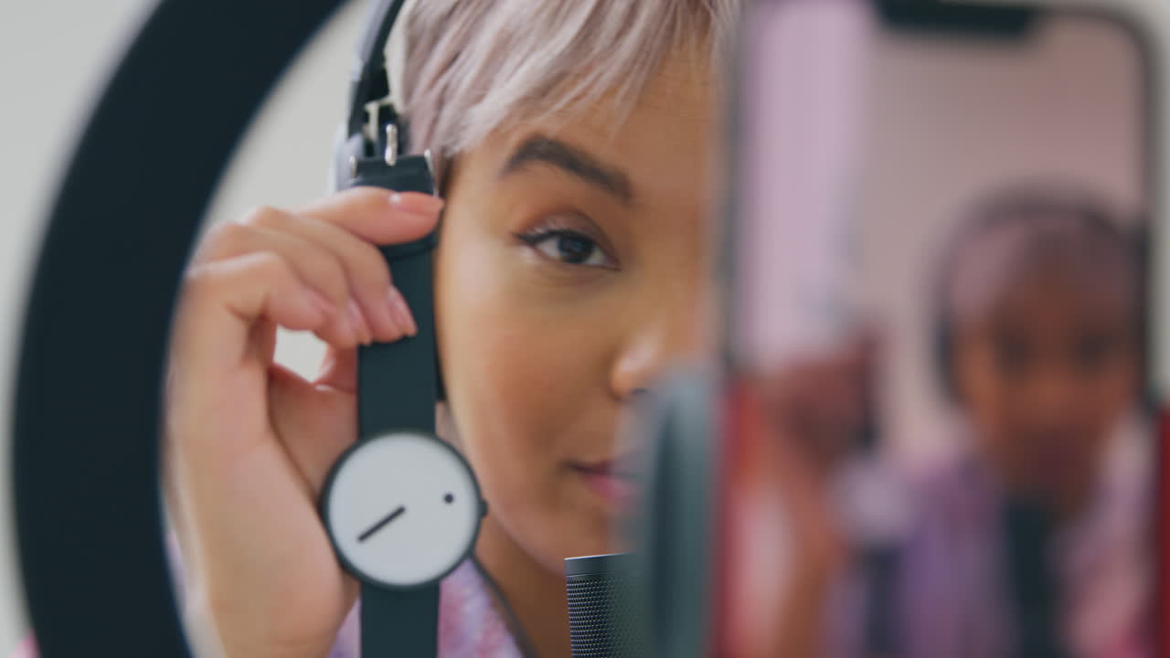 vlogger femenina grabando un video de revisión de producto de reloj de muñeca en casa con teléfono móvil