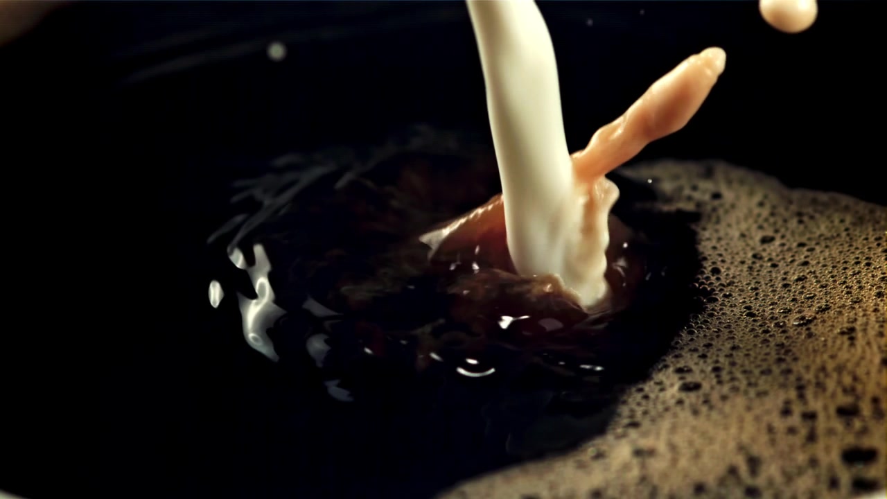 Versamento al rallentatore di latte nel caffè nero con schiuma