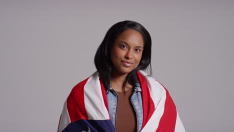 retrato de estudio de una mujer envuelta en la bandera estadounidense celebrando el 4 de julio, día de la independencia.