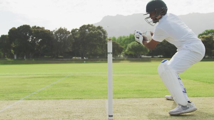 Vista laterale di un giocatore di cricket che afferra la palla.