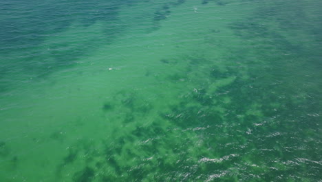 Wide-aerial-footage-of-the-green-and-blue-of-the-Mediterranean-Sea-with-boats-floating-amongst-the-waves