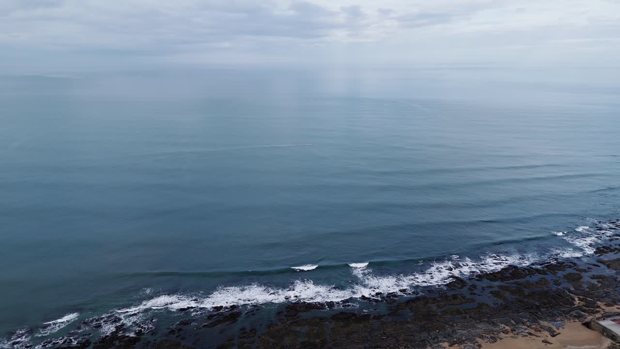long quiet coast with gentle waves meeting rock formations at twilight