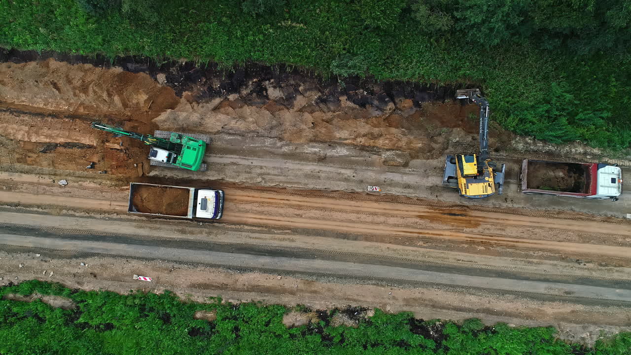 vista aérea de arriba hacia abajo sobre maquinaria y camiones de trabajo de construcción de carreteras