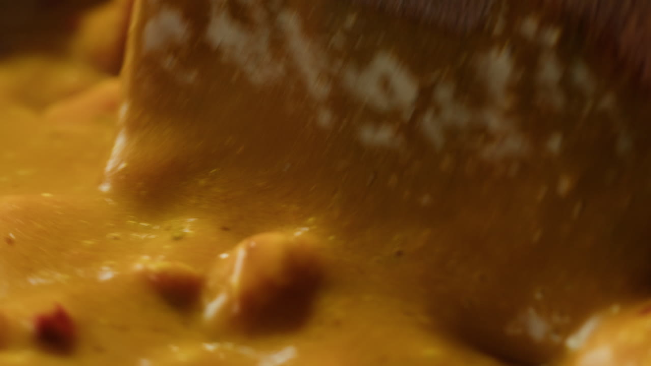 Yellow boiling sauce on pan close-up. Asian cuisine concept. Curry is a dish with a sauce seasoned with spices. Curries may contain fish, meat, poultry, or shellfish, either alone or in combination with vegetables. Others are vegetarian.