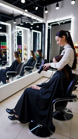 hairstylist blow-drying client's hair in a salon