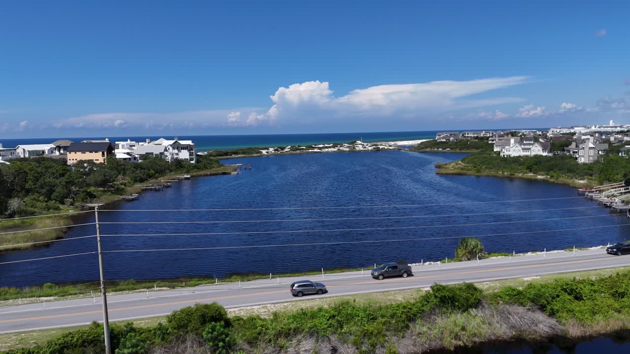 Aerial fly crossing the County Rd 30A highway at blue coastal Camp Creek Lake towards the ocean, 30A, Florida, USA