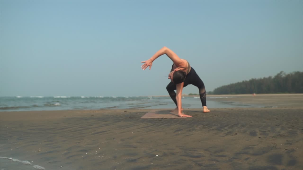 mujer haciendo ejercicios de yoga en la orilla de una playa