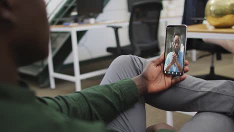 african american businessman using smartphone for video call with business colleague