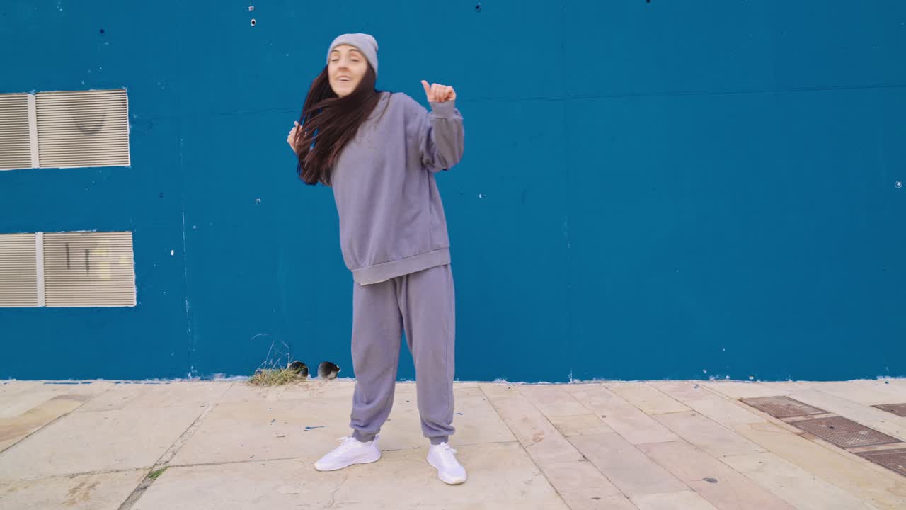 Woman dancing in front of a blue wall