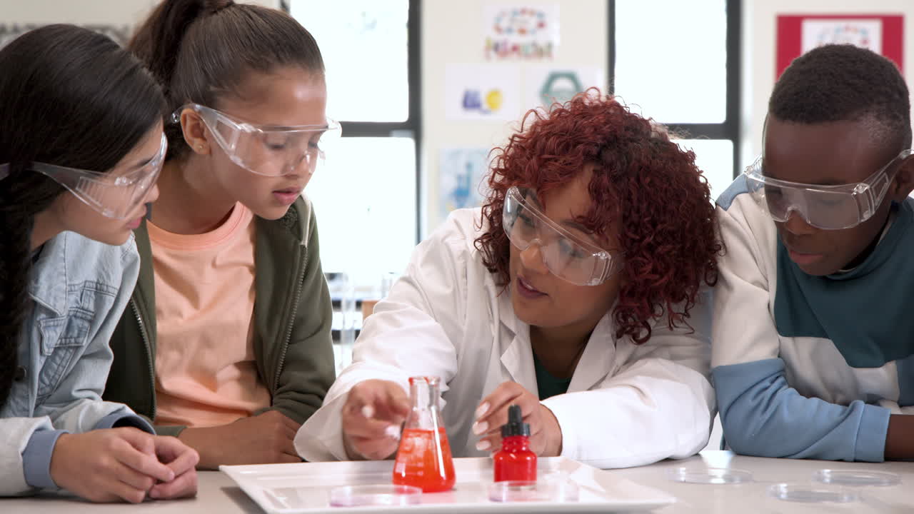 Multiracial students and female teacher in science class observing chemical reaction, at school