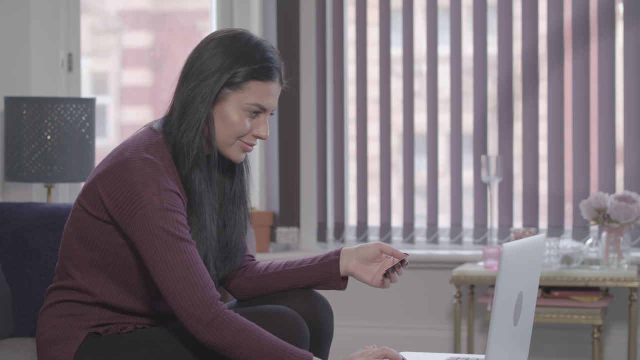 la joven sentada en casa usa un cuaderno para comprar en línea y sonríe