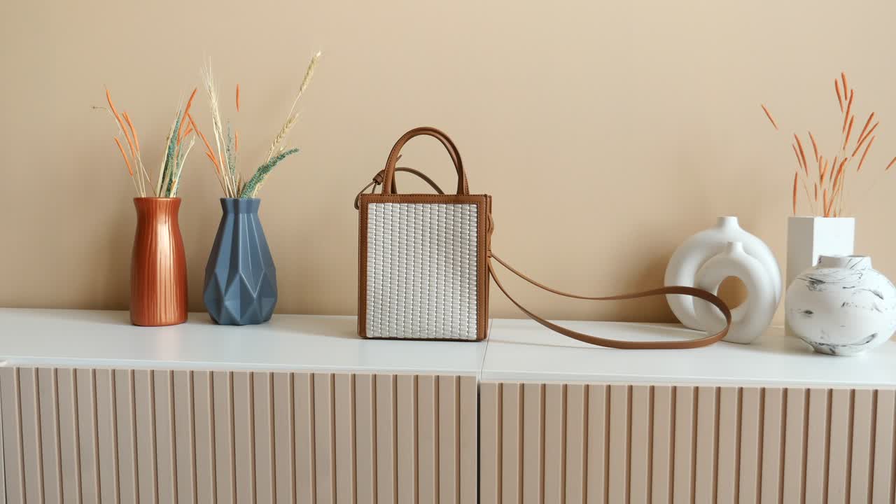 색 선반 에 꽃병 과 건조 한 꽃 을 가진 색 가죽 의  가방