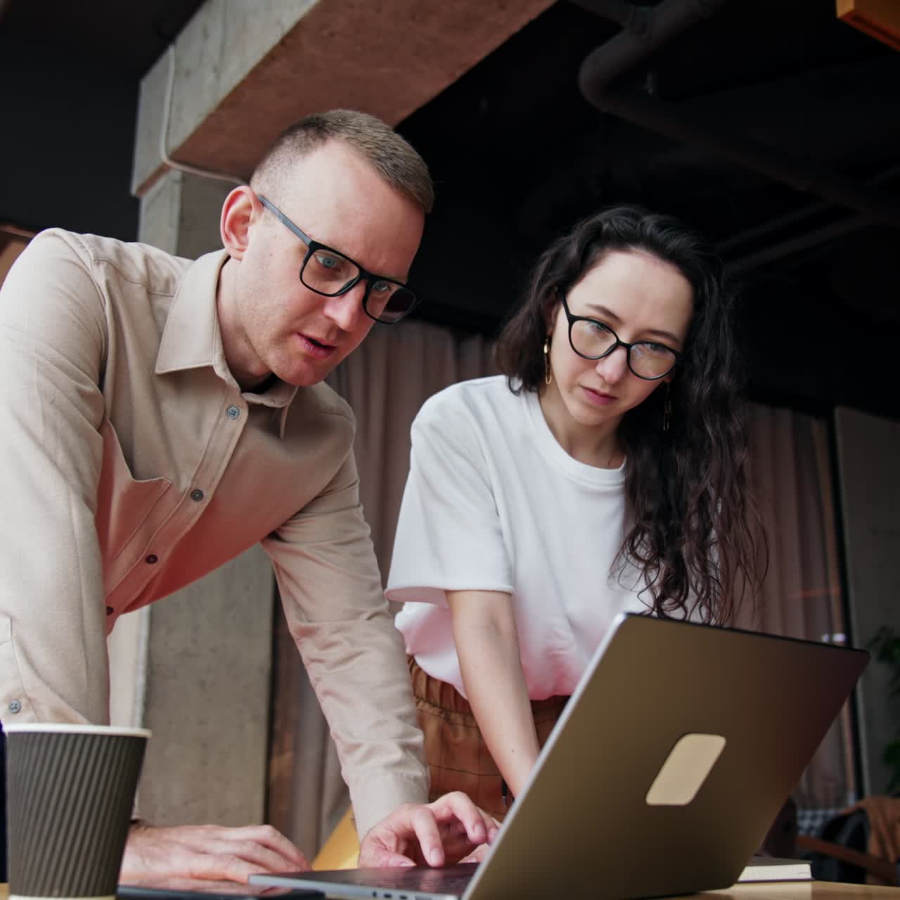 Coworkers stand bent over the laptop discussing the problem. Work on a project in the office. Low angle view