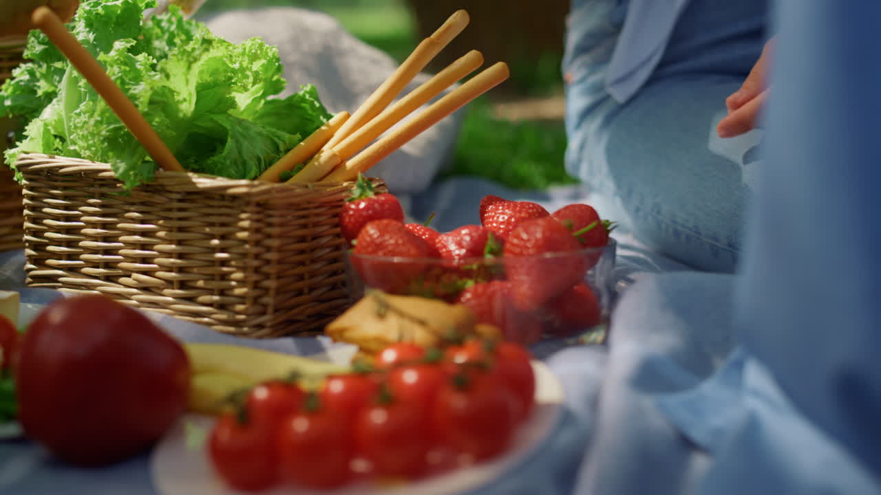 인식되지 않은 손은 피크닉 클로즈업에서 딸기를 잡습니다. 여성의 팔은  ⁇ 은 베리를 잡습니다.