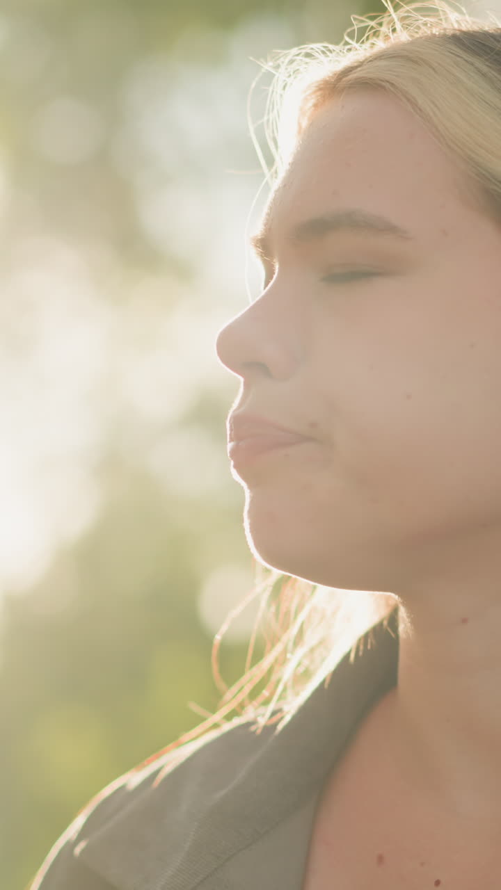 mujer sentada al aire libre bebiendo jugo de naranja de la botella con satisfacción relajada, su expresión refleja satisfacción, el fondo muestra un brillo suave de la luz solar, árboles y vegetación